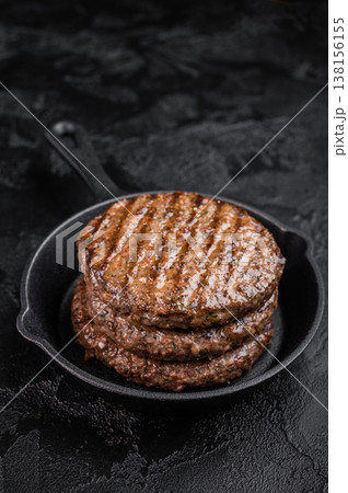 Grilled beef and lamb hamburger patty with seared crust and juicy texture in cast iron skillet. Cooked mixed meat on dark stone background. Grilled beef and lamb hamburger patty with seared crust and juicy texture in cast iron skillet. Cooked mixed meat on dark stone background. 138156155