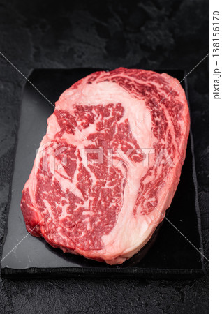Fresh raw ribeye beef steak, marbled rib fillet cut, premium red meat for grilling roasting or steakhouse cooking on dark background Fresh raw ribeye beef steak, marbled rib fillet cut, premium red meat for grilling roasting or steakhouse cooking on dark background 138156170