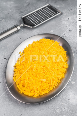 Grated cheddar cheese in metal bowl over concrete surface food ingredient texture with copy space for menu or recipe 138156175