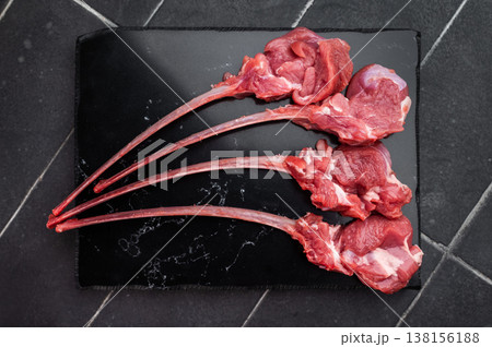 Fresh uncooked lamb chops with bone and peppercorns on slate board dark background overhead food ingredient 138156188