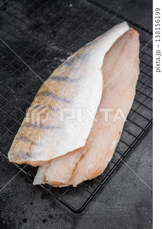 Raw pike perch fillets on dark background, one skin-on and one skinless, fresh freshwater white fish meat ready for cooking. 138156199