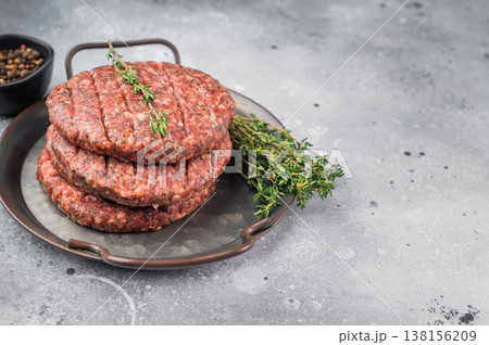 Raw Uncooked beef lamb minced meat patty with herbs and pepper in pan. Overhead view on light stone background with copy space. 138156209