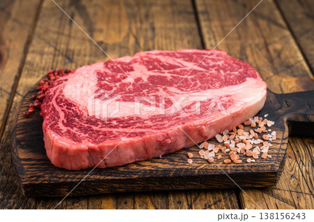 Fresh raw ribeye beef steak entrecote style with rich marbling. Premium rib fillet meat on wooden background. Fresh raw ribeye beef steak entrecote style with rich marbling. Premium rib fillet meat on wooden background. 138156243
