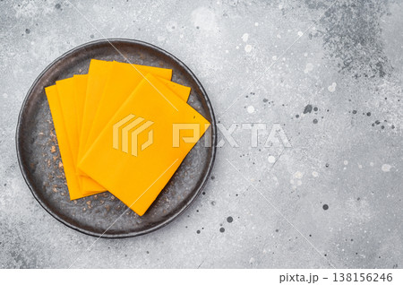Stack of orange cheese slices on round plate minimal food composition with copy space for menu design or recipes Stack of orange cheese slices on round plate minimal food composition with copy space for menu design or recipes 138156246