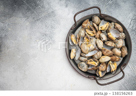 Italian vongole clams arranged in rustic metal pan. Fresh seafood dish with shells on light background, top view. 138156263