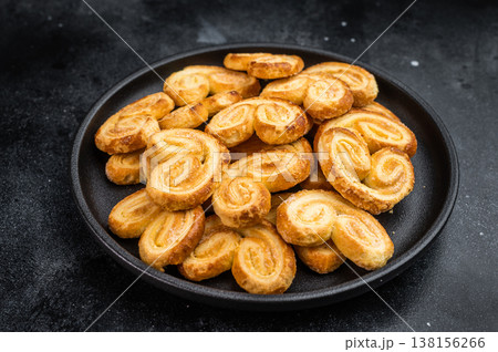 Classic French palmier cookies made from puff pastry in black bowl dark background sweet baked dessert concept Classic French palmier cookies made from puff pastry in black bowl dark background sweet baked dessert concept 138156266