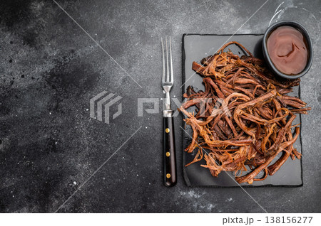 Smoked shredded brisket meat on black stone tray, dried beef strips snack, barbecue style protein food. Smoked shredded brisket meat on black stone tray, dried beef strips snack, barbecue style protein food. 138156277