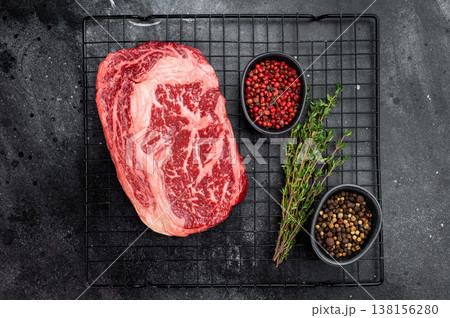 Uncooked raw rib eye steak rib fiilet cut entrecote style with visible fat marbling. Fresh beef on black background. Uncooked raw rib eye steak rib fiilet cut entrecote style with visible fat marbling. Fresh beef on black background. 138156280