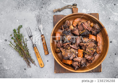 Slow cooked oxtails with vegetables, thyme and rosemary, hearty comfort food in rustic wooden bowl, top view 138156288
