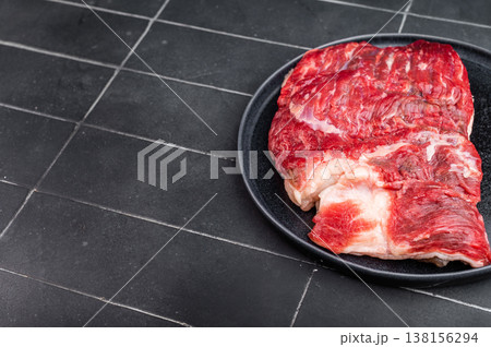 Raw beef brisket on dark plate with peppercorns and salt, top view minimalist food background with copy space Raw beef brisket on dark plate with peppercorns and salt, top view minimalist food background with copy space 138156294