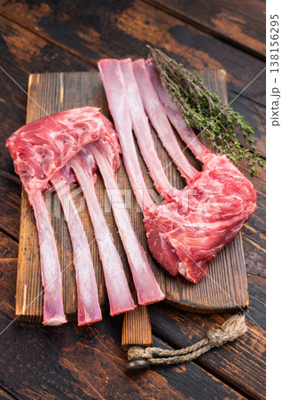 Raw lamb rack ribs with bone on rustic wooden board dark background top view butcher style meat with copy space Raw lamb rack ribs with bone on rustic wooden board dark background top view butcher style meat with copy space 138156295