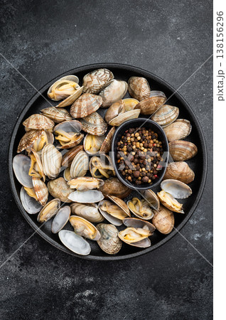 Cooked vongole clams served in cast iron skillet with spices on dark background. Italian seafood dish with open shells. Cooked vongole clams served in cast iron skillet with spices on dark background. Italian seafood dish with open shells. 138156296