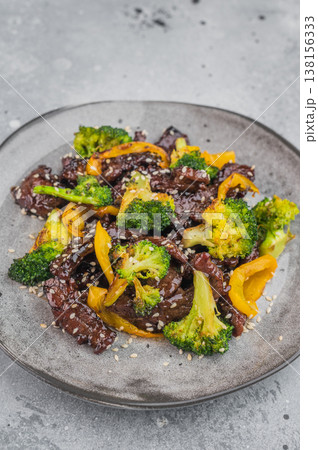 Beef and broccoli stir fry with sesame seeds and bell pepper served on gray plate isolated on white background Beef and broccoli stir fry with sesame seeds and bell pepper served on gray plate isolated on white background 138156333