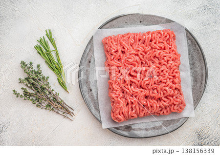 Raw minced pork and beef ground meat portion on parchment paper on plate isolated on light background with copy space 138156339