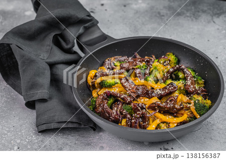Beef stir fry with broccoli and yellow bell pepper in sesame sauce cooked in wok style pan on gray background. Beef stir fry with broccoli and yellow bell pepper in sesame sauce cooked in wok style pan on gray background. 138156387