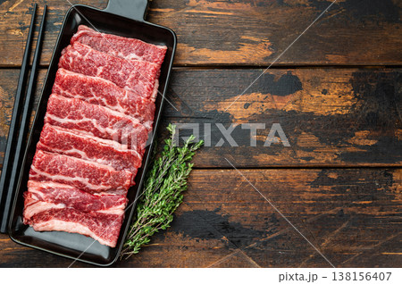 Marbled beef slices prepared for Korean BBQ grilling, raw premium meat on slate board with chopsticks, dark background 138156407