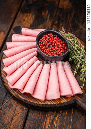 Gourmet charcuterie board featuring fan folded bologna/mortadella, pink peppercorns, and fresh thyme on dark wood. Gourmet charcuterie board featuring fan folded bologna/mortadella, pink peppercorns, and fresh thyme on dark wood. 138156519