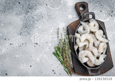Frozen raw shrimp prawns in a rustic skillet with fresh thyme on a gray stone background. Flat lay with copy space. 138156528