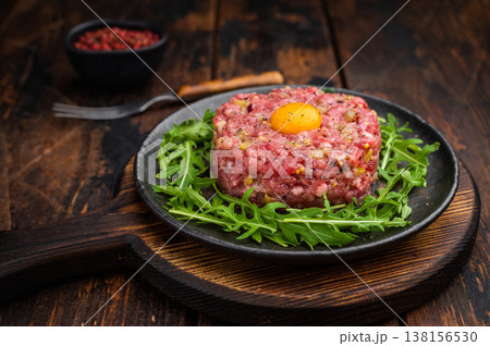 Fresh steak tartare served with greens mustard and pickles on dark plate ideal for culinary ads fine dining visuals and recipe content. Fresh steak tartare served with greens mustard and pickles on dark plate ideal for culinary ads fine dining visuals and recipe content. 138156530