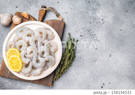 Raw shrimp prawn with lemon, garlic, and thyme on a textured grey background. Top view of seafood preparation with copy space. Raw shrimp prawn with lemon, garlic, and thyme on a textured grey background. Top view of seafood preparation with copy space. 138156531