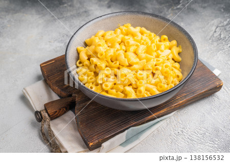 Savory mac and cheese served in a stylish bowl. Wooden board and gray background create a cozy, modern food scene. 138156532