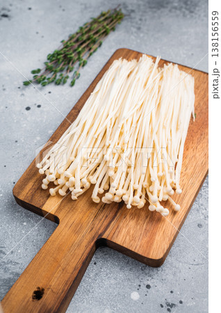 Cooking preparation flat lay Enoki fungi, fresh thyme, and garlic on a rustic board and modern concrete surface. Cooking preparation flat lay Enoki fungi, fresh thyme, and garlic on a rustic board and modern concrete surface. 138156559