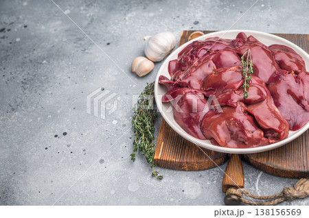 Close-up of fresh chicken liver with a knife and herbs, displayed on a textured gray surface. Ideal for food blog visuals. Close-up of fresh chicken liver with a knife and herbs, displayed on a textured gray surface. Ideal for food blog visuals. 138156569
