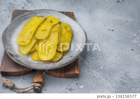 Crisp marinated cucumber slices seasoned with dill and mustard seeds on ceramic plate, top view over stone background. Crisp marinated cucumber slices seasoned with dill and mustard seeds on ceramic plate, top view over stone background. 138156577