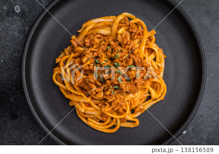 Delicious ragu pasta with herbs and parmesan on a dark stone backdrop, styled with vintage fork and fresh thyme, top view. Delicious ragu pasta with herbs and parmesan on a dark stone backdrop, styled with vintage fork and fresh thyme, top view. 138156589