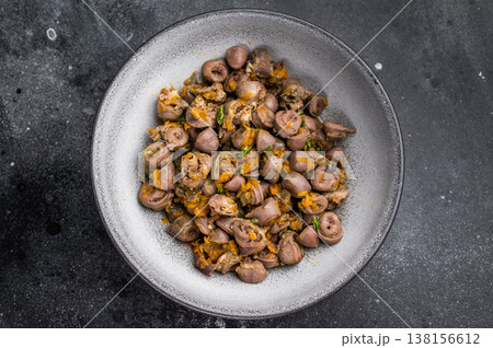 Tasty giblets stew served in gray plate on textured black surface ideal for culinary blogs or traditional meal visuals. Tasty giblets stew served in gray plate on textured black surface ideal for culinary blogs or traditional meal visuals. 138156612