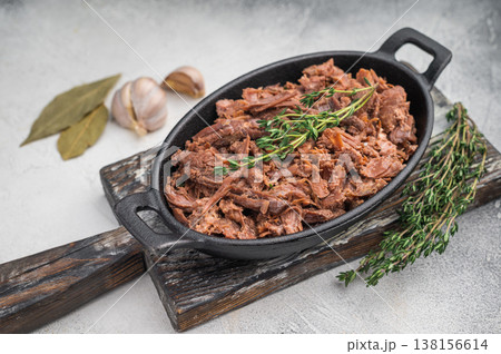 Tender slow cooked venison and elk stew with herbs in a cast iron dish on a light textured background for rustic gourmet food concepts. Tender slow cooked venison and elk stew with herbs in a cast iron dish on a light textured background for rustic gourmet food concepts. 138156614