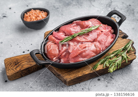Raw quail breast fillets with rosemary and pink salt in a cast iron pan on a wooden board. Rustic gourmet food preparation. Raw quail breast fillets with rosemary and pink salt in a cast iron pan on a wooden board. Rustic gourmet food preparation. 138156616