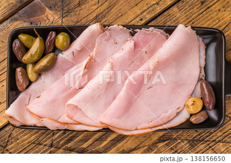 Gourmet pork cold cuts and olives displayed on a dark serving tray over vintage wooden planks offering space for text and advertising needs. Gourmet pork cold cuts and olives displayed on a dark serving tray over vintage wooden planks offering space for text and advertising needs. 138156650
