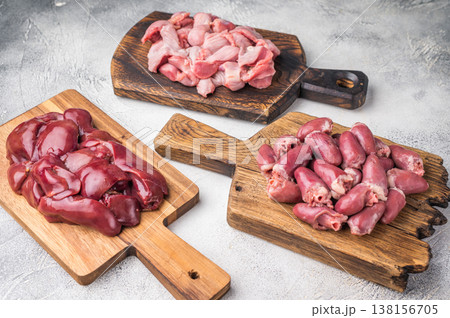 Assorted raw giblets including hearts, liver, and gizzards on vintage wooden boards, organic poultry cooking concept. Assorted raw giblets including hearts, liver, and gizzards on vintage wooden boards, organic poultry cooking concept. 138156705