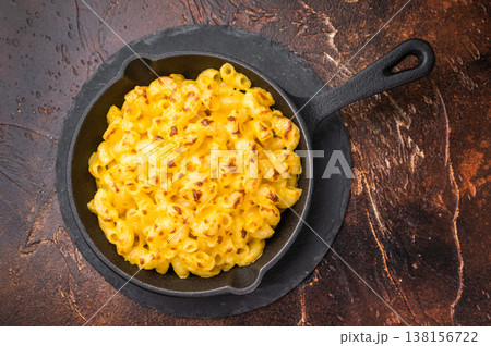 Baked mac and cheese in a black skillet, set against a rustic dark brown background 138156722