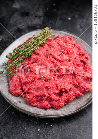 Raw ground wild game meat rabbit hare on a textured grey plate with fresh thyme, set on a dark, moody stone background. Raw ground wild game meat rabbit hare on a textured grey plate with fresh thyme, set on a dark, moody stone background. 138156731