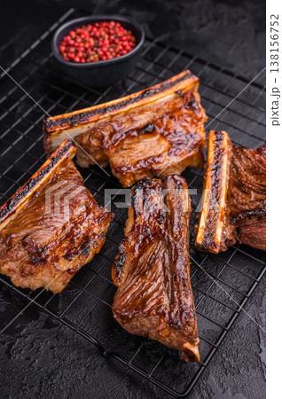 High contrast BBQ ribs shot with pink peppercorns. Dark and moody food photography for web banners. High contrast BBQ ribs shot with pink peppercorns. Dark and moody food photography for web banners. 138156752