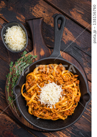Rustic pasta bolognese with rich meat ragu and parmesan served in a cast iron skillet on dark wooden background with fresh thyme. 138156760
