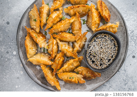Crispy pan fried jiaozi dumplings with sesame served on dark plate. Asian mandu potstickers Crispy pan fried jiaozi dumplings with sesame served on dark plate. Asian mandu potstickers 138156768