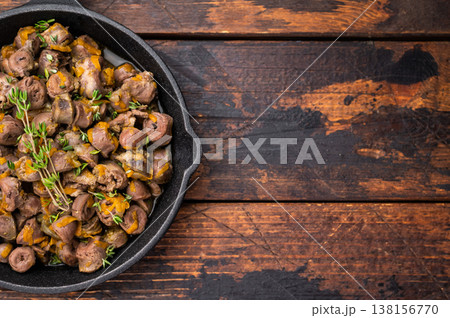 Tasty chicken offal stew in cast iron pan on dark wooden surface great for restaurant advertising or food blogs. Tasty chicken offal stew in cast iron pan on dark wooden surface great for restaurant advertising or food blogs. 138156770