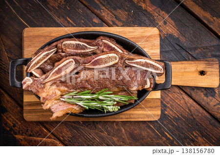 Grilled beef short ribs (Flanken/Galbi) with rosemary and garlic. Served on a wooden background with copy space. Grilled beef short ribs (Flanken/Galbi) with rosemary and garlic. Served on a wooden background with copy space. 138156780