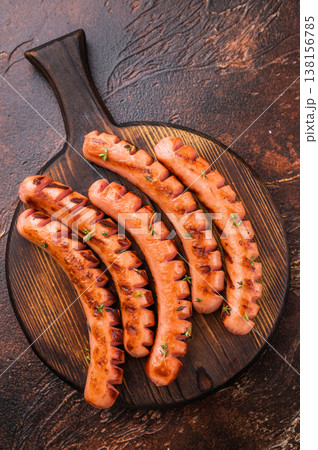 Grilled and cut sausages (frankfurters/wieners) seasoned with thyme, served on a dark wooden board with Himalayan salt. Ready meal. Grilled and cut sausages (frankfurters/wieners) seasoned with thyme, served on a dark wooden board with Himalayan salt. Ready meal. 138156785