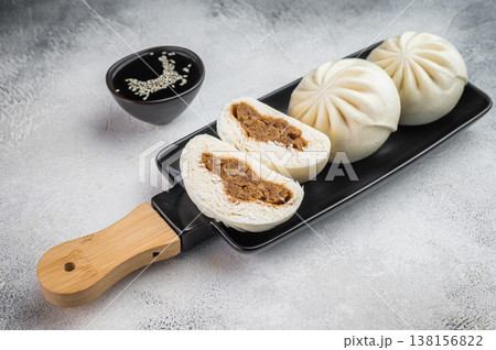 Nikuman steamed buns with visible meat filling on black dish, Asian street food composition with vertical layout and copy space 138156822