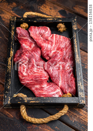 Closeup raw skirt beef steak with visible fibers and marbling on dark wooden background with rosemary and spices, uncooked protein ingredient for grilling Closeup raw skirt beef steak with visible fibers and marbling on dark wooden background with rosemary and spices, uncooked protein ingredient for grilling 138156838