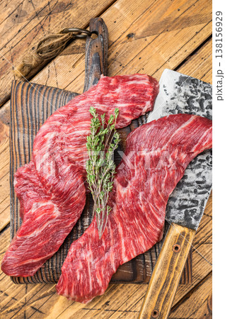 Fresh raw premium beef meat steak slices with visible marbling on wooden surface with butcher knife and rosemary, ingredient for cooking grilling or barbecue Fresh raw premium beef meat steak slices with visible marbling on wooden surface with butcher knife and rosemary, ingredient for cooking grilling or barbecue 138156929
