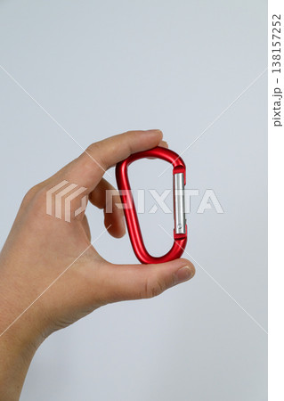 赤いカラビナを持つ手と白背景の余白 138157252