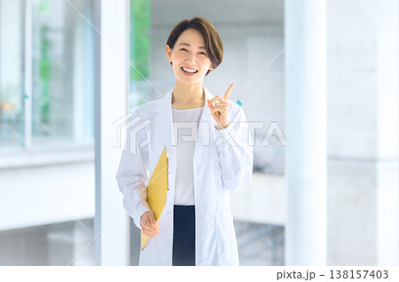 笑顔で指を差しアドバイスをする白衣の日本人女性医師 病院 クリニック 医療 笑顔で指を差しアドバイスをする白衣の日本人女性医師 病院 クリニック 医療 138157403