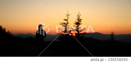 Silhouette of person standing on mountain ridge during sunset 138158293