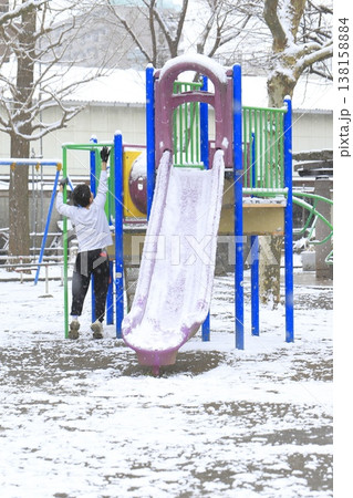 雪の降る日の公園と遊具で遊ぶ子供 138158884