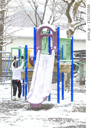雪の降る日の公園と遊具で遊ぶ子供 138158886